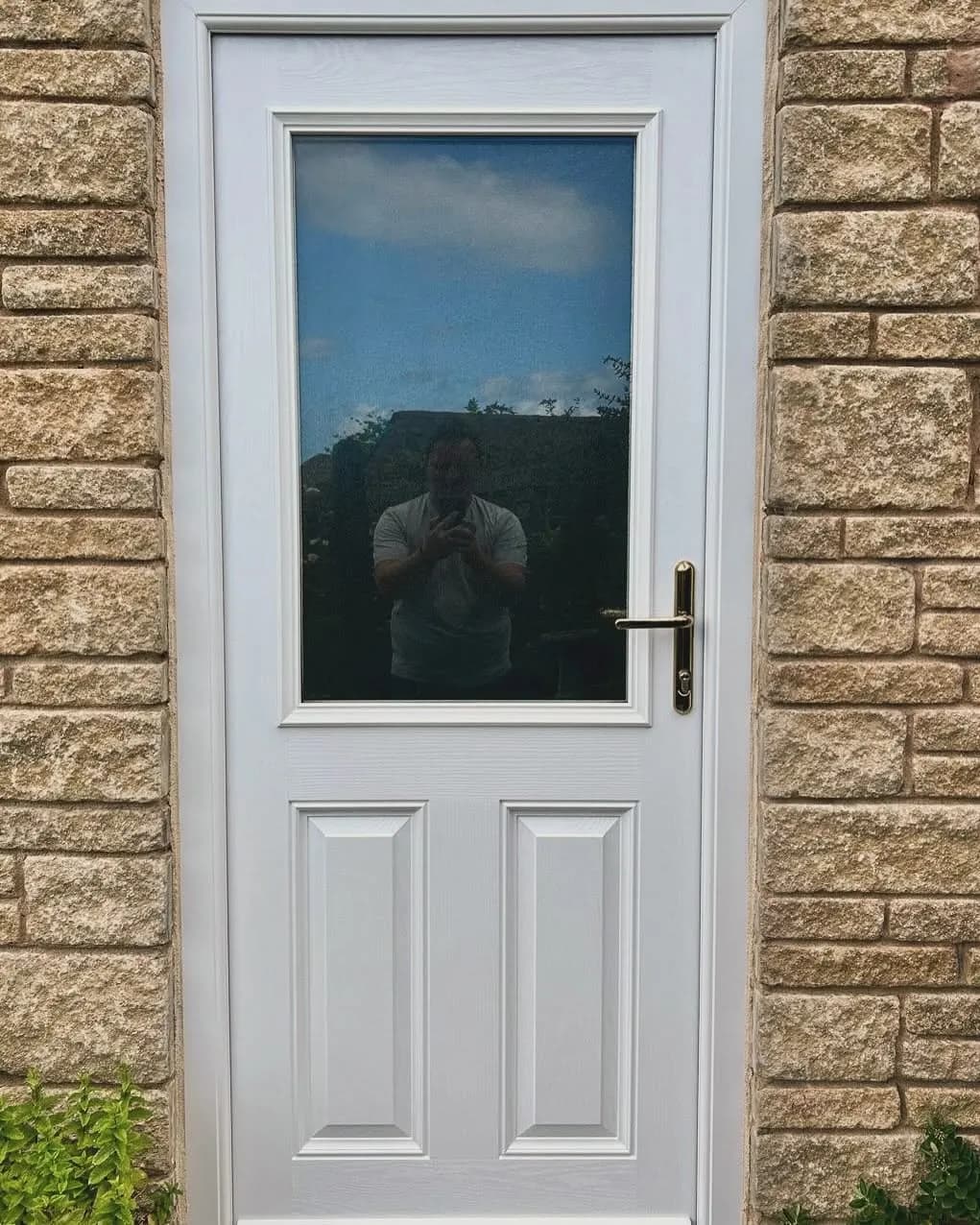 A white composite front door with a glazed panel